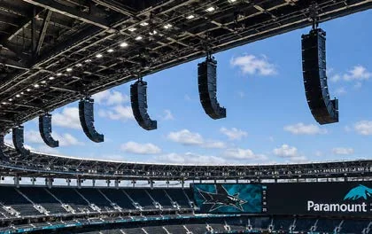 Line-array loudspeakers suspended from a stadium roof structure